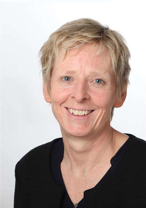 Porträtaufnahme einer blonden Frau, die in die Kamera lächelt.